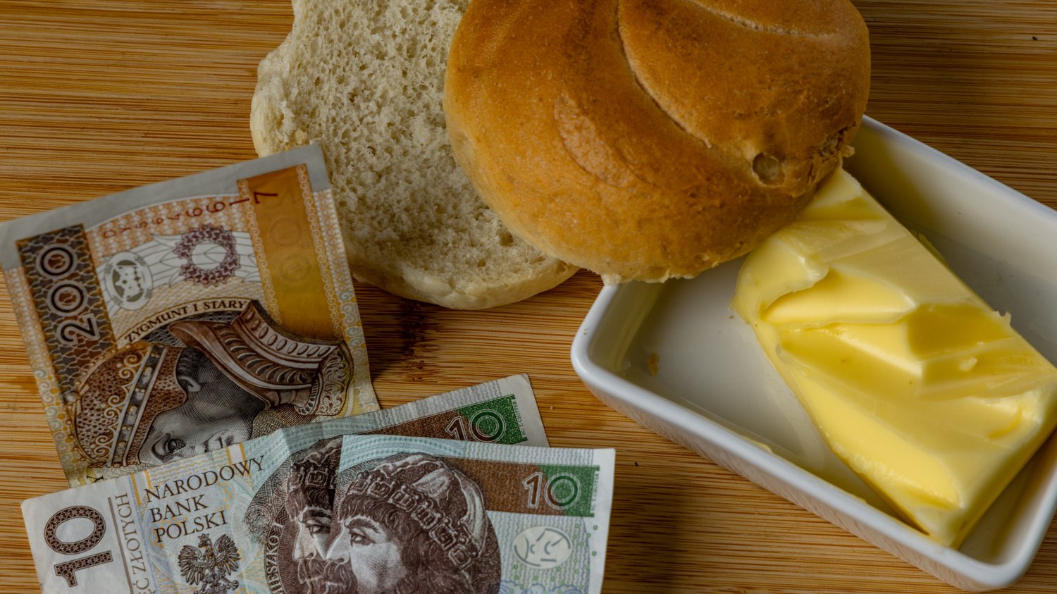 Bułka, masło i banknoty polskich złotych. Ceny masła w dół. Płacimy mniej choć wcześniej było liderem drożyzny