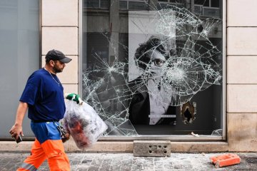 Człowiek przed zdewastowaną witryną sklepową.