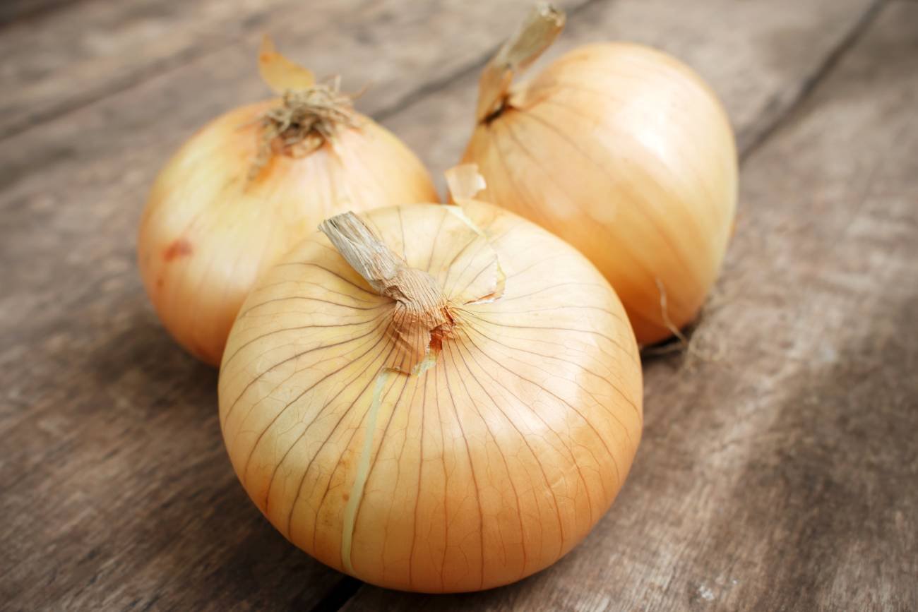 Główki cebuli na drewnianym blacie.