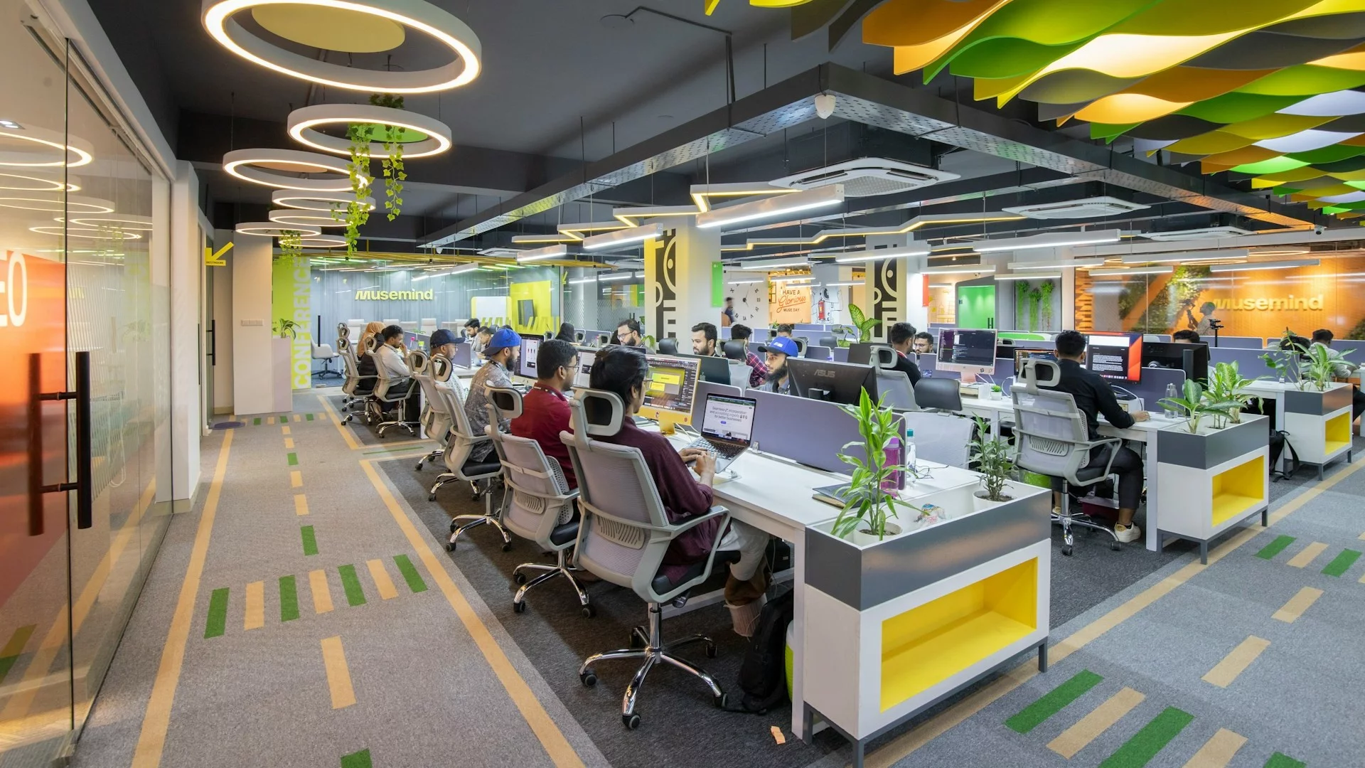 Rzędy ludzi pracujących przy biurkach w dużym pomieszczeniu. Rząd Niemiec chce wydłużyć czas pracy.