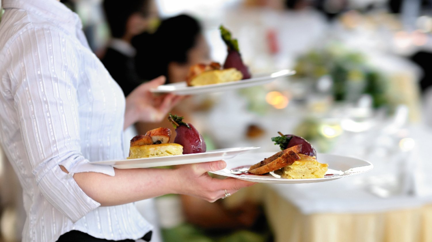 kelnerka w białej koszuli niesie talerze z jedzeniem dla klientów restauracji