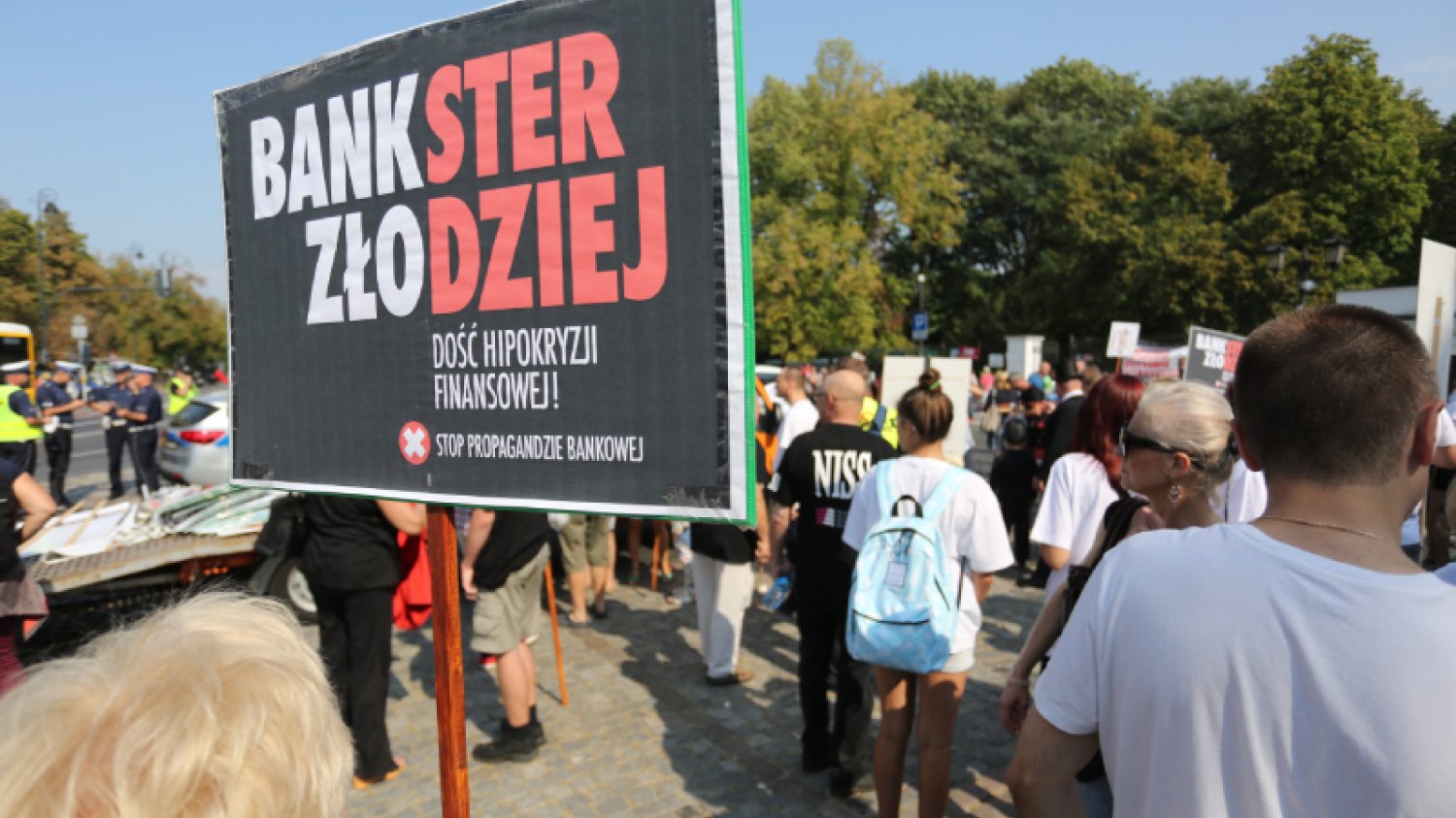 Demonstracja frankowiczów przeciwko bankom. Na pierwszym planie baner z biało-czerwonym napisem "bankster złodziej"