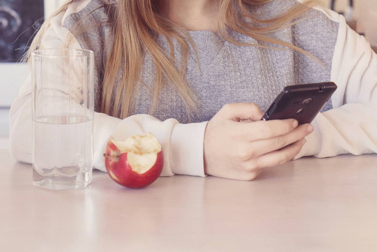 Nastolatka z telefonem i jabłkiem.