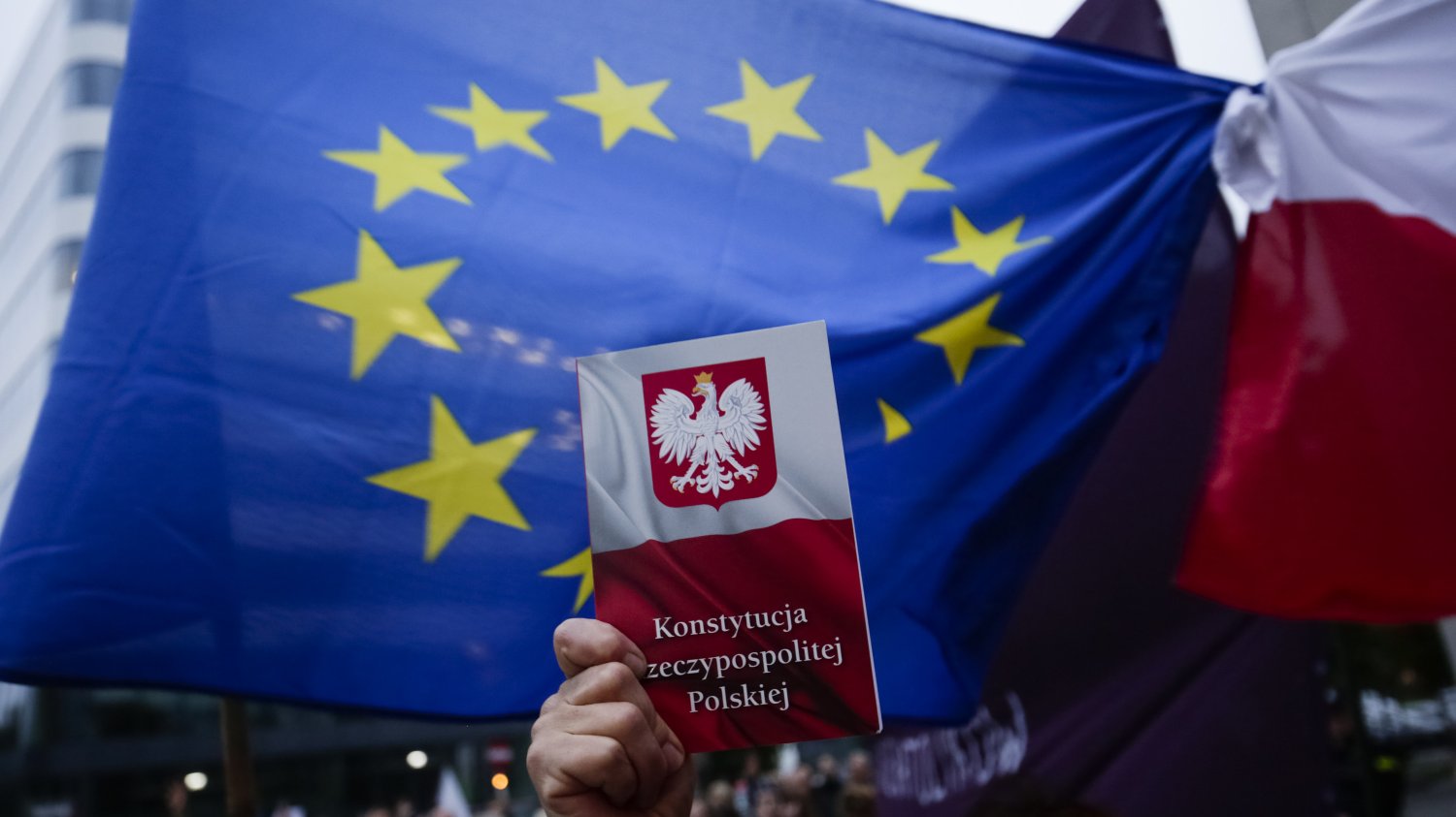 Europejska flaga i polska konstytucja trzymana w dłoni