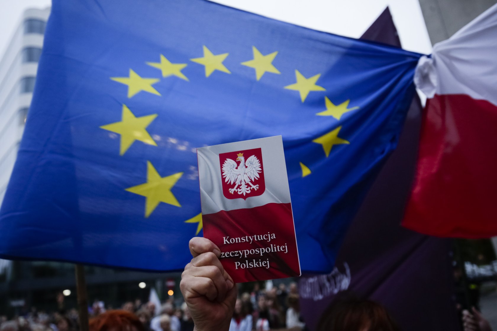 Europejska flaga i polska konstytucja trzymana w dłoni