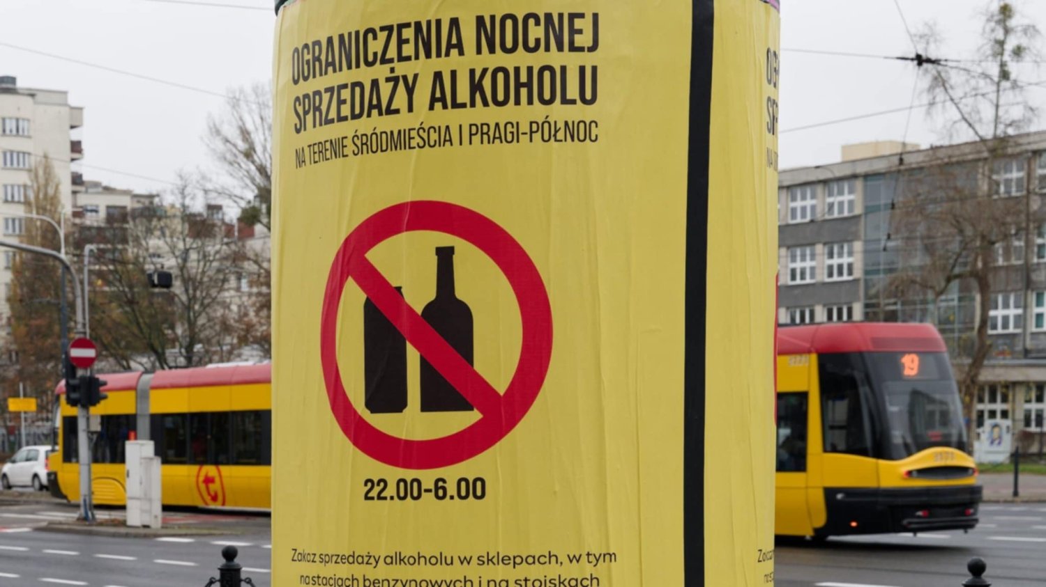 Słup ogłoszeniowy z warszawskim plakatem mówiącym o prohibicji. W tle tramwaj
