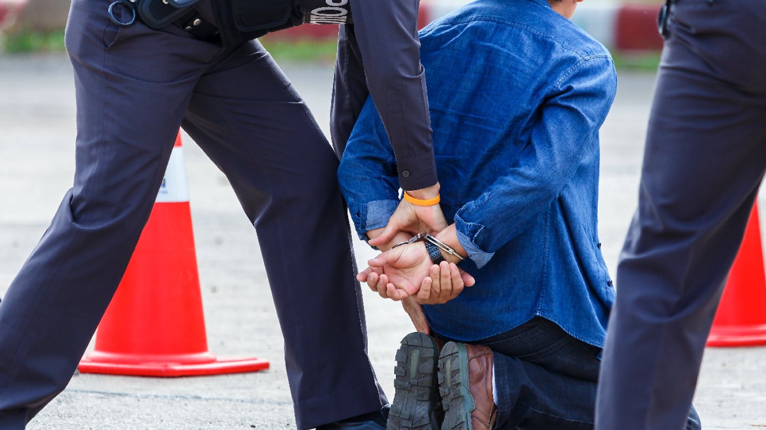 policja zakłada kajdanki mężczyźnie w niebieskiej koszuli