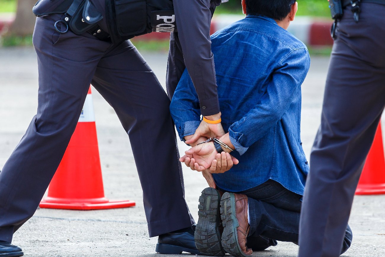 policja zakłada kajdanki mężczyźnie w niebieskiej koszuli