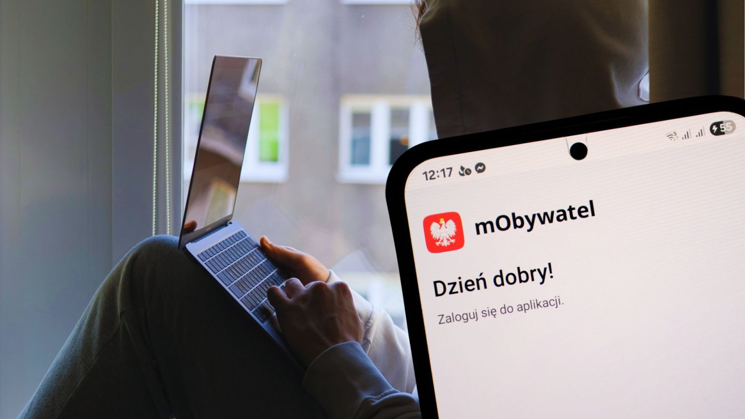Nastolatkowie sprzedali „lewego” mObywatela ponad 3 tys. osób. Bezczelne oszustwo ukrócone Zakapturzony człowiek z laptopem oraz telefon z aplikacją mObywatel. 3 tysiące osób kupiło fałszywego mObywatela. Nastolatkowie zostali aresztowani