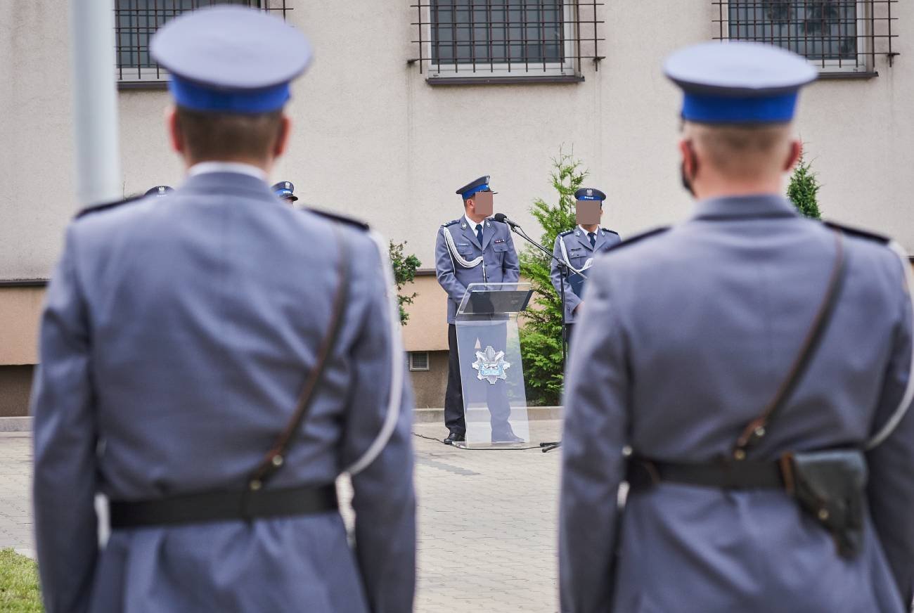 Policjanci w mundurach stoją przed budynkiem.