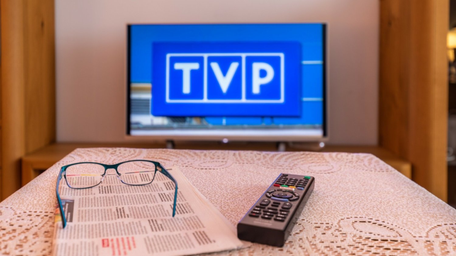 Telewizor, pilot, gazeta, okulary, stół.