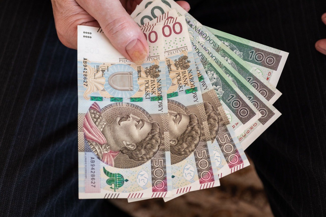 Polskie banknoty w ręku mężczyzny.