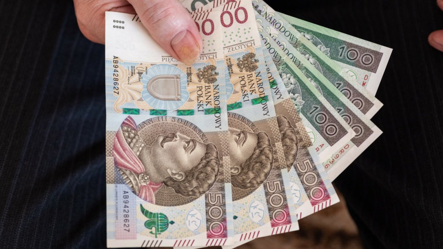 Polskie banknoty w ręku mężczyzny.