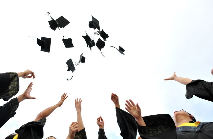 Żakowie podrzucają do góry birety absolwenckie.