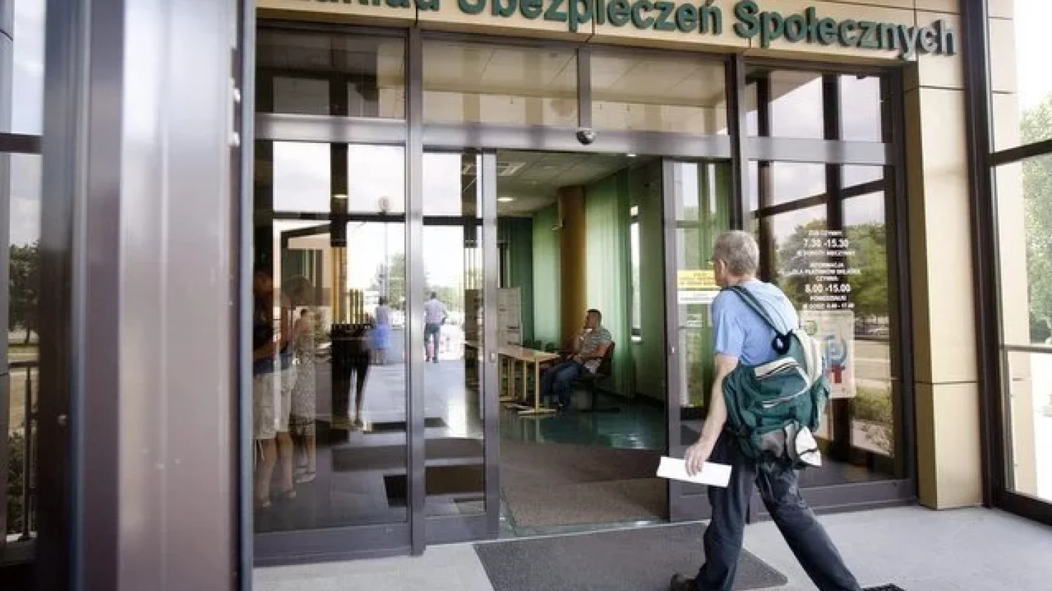 Mężczyzna z plecakiem wchodzący do Zakładu Ubezpieczeń Społecznych