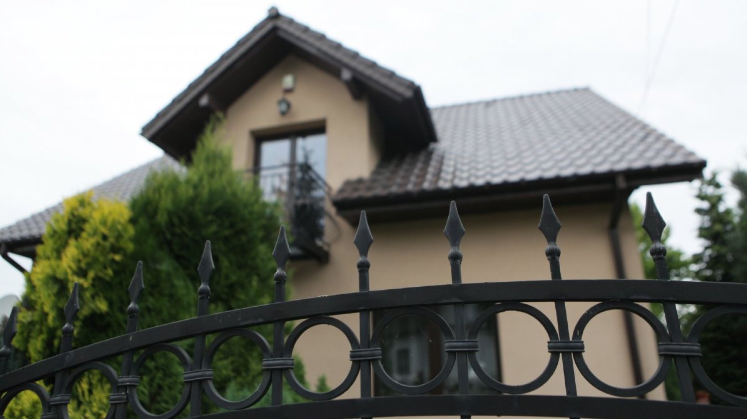 Nowy dom za metalowym ogrodzeniem.