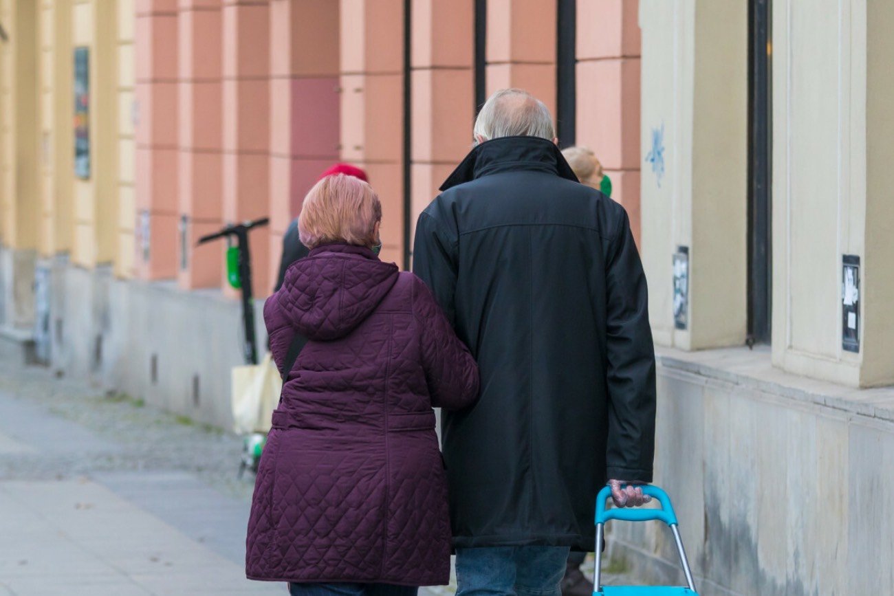 Seniorzy idący z torbą na kółkach po zakupy do sklepu