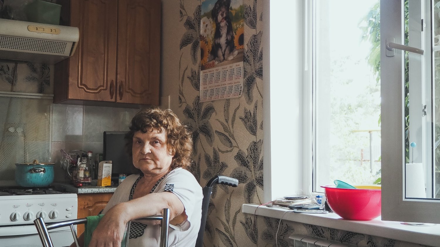 Stara kobieta siedzi na wózku inwalidzkim w swojej kuchni