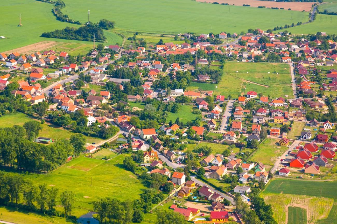 Miasteczko widziane z lotu ptaka. Tereny zielone wokół budynków z czerwonymi dachami.