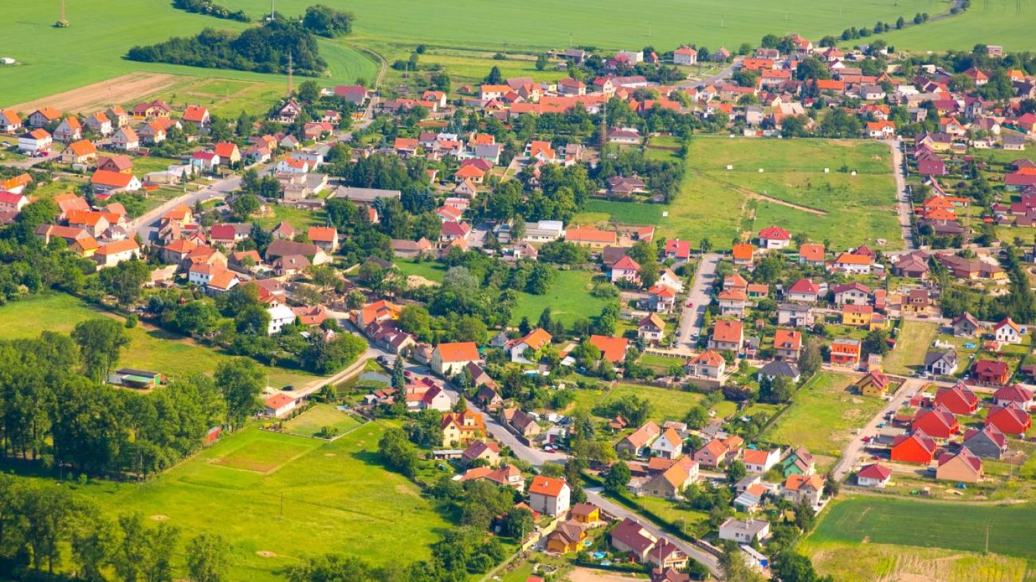 Miasteczko widziane z lotu ptaka. Tereny zielone wokół budynków z czerwonymi dachami.