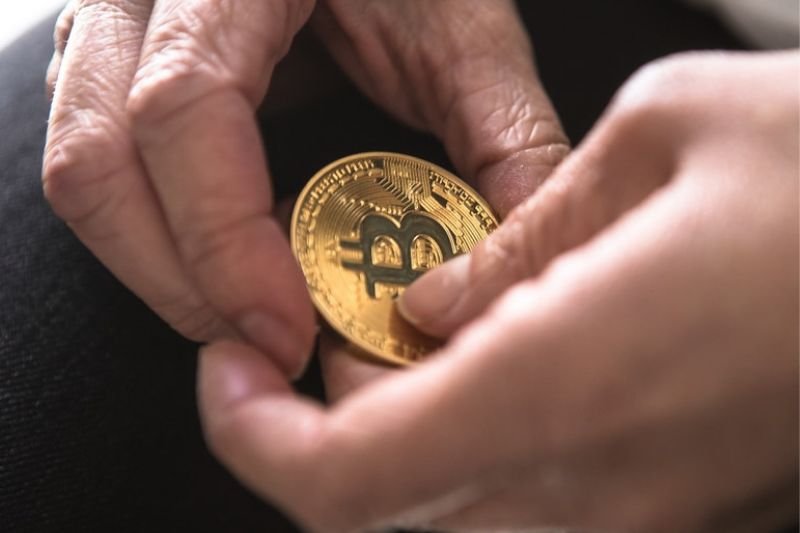 Moneta bitcoin w dłoniach.