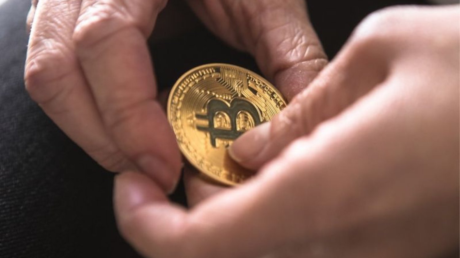 Moneta bitcoin w dłoniach.