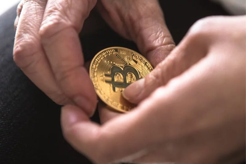Moneta bitcoin w dłoniach.