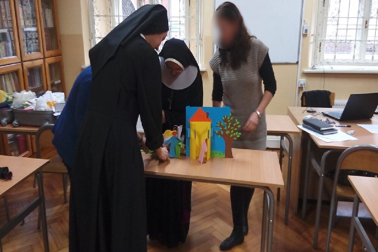 Zakonnice i kobieta w klasie przy szkolnej ławce