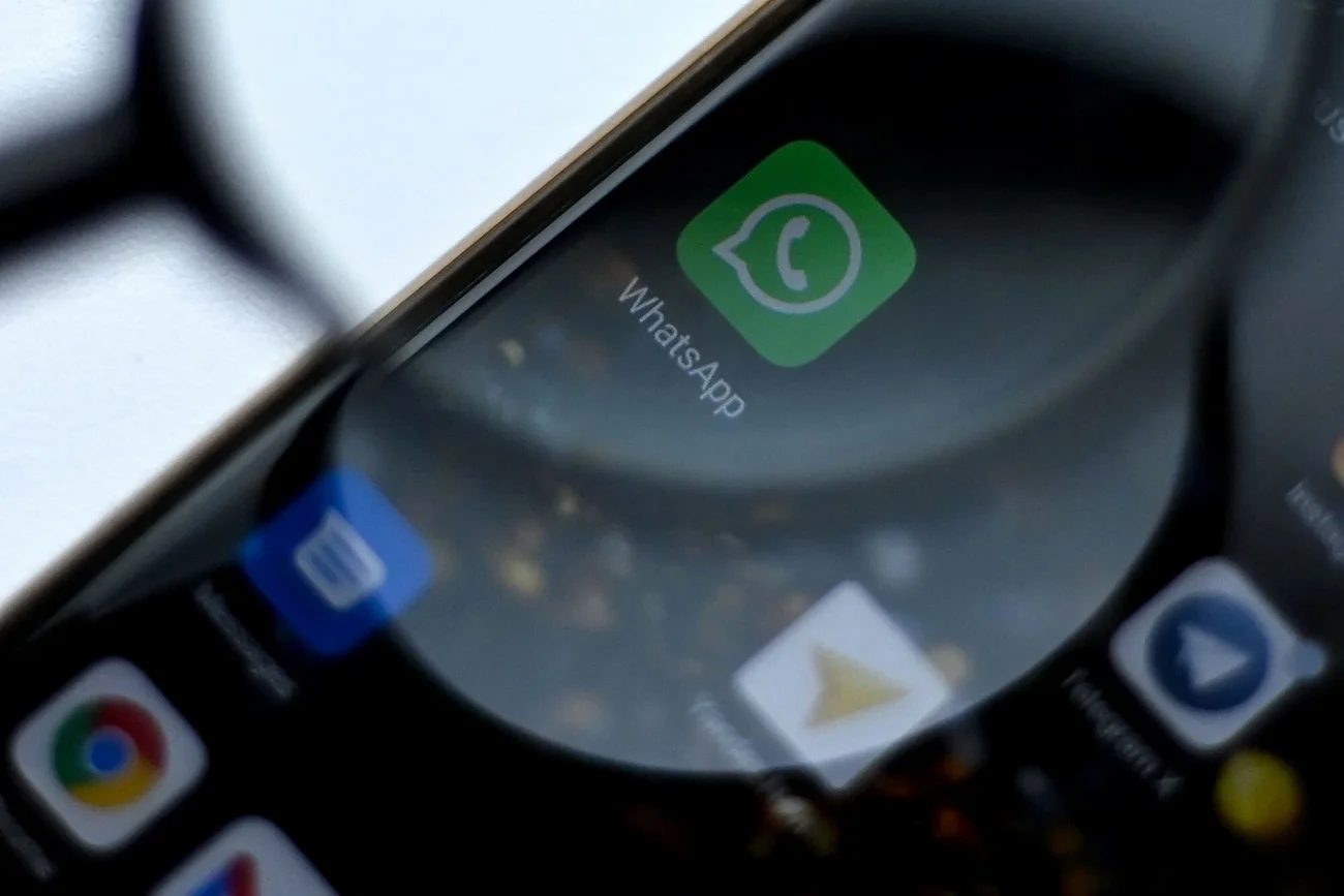 Lupa przybliżona do smartfonu z ikoną WhatsApp.
