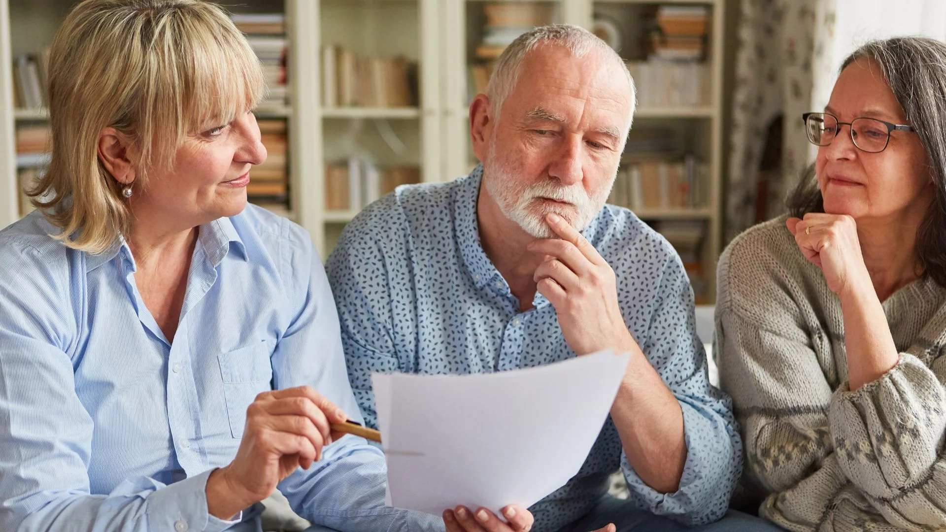 Kobieta prezentuje emerytom dokument. Omawiamy petycję Sejmową o zrównanie wieku emerytalnego do 62 lat dla obu płci.