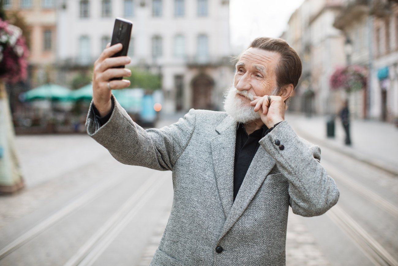 Starszy mężczyzna robi sobie selfie na ulicy.