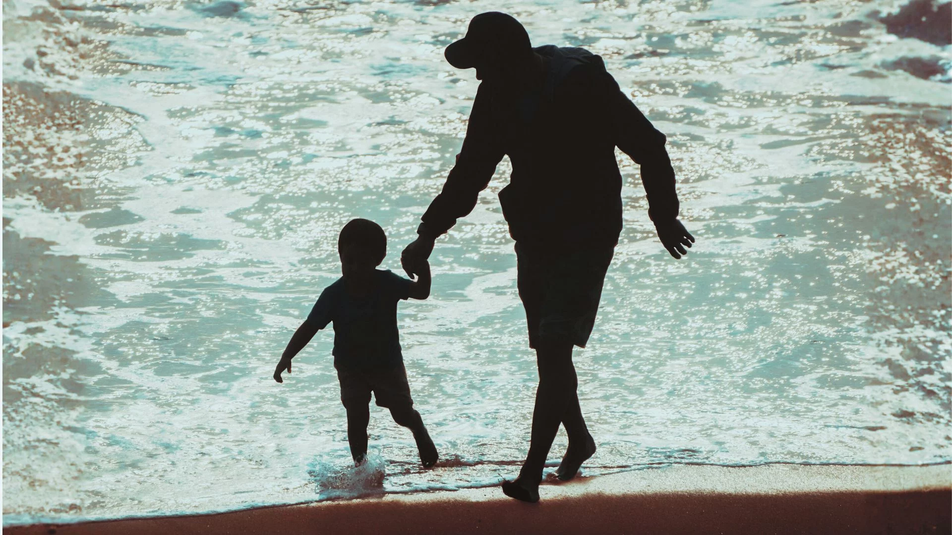 Ojciec z dzieckiem bawią się na plaży.