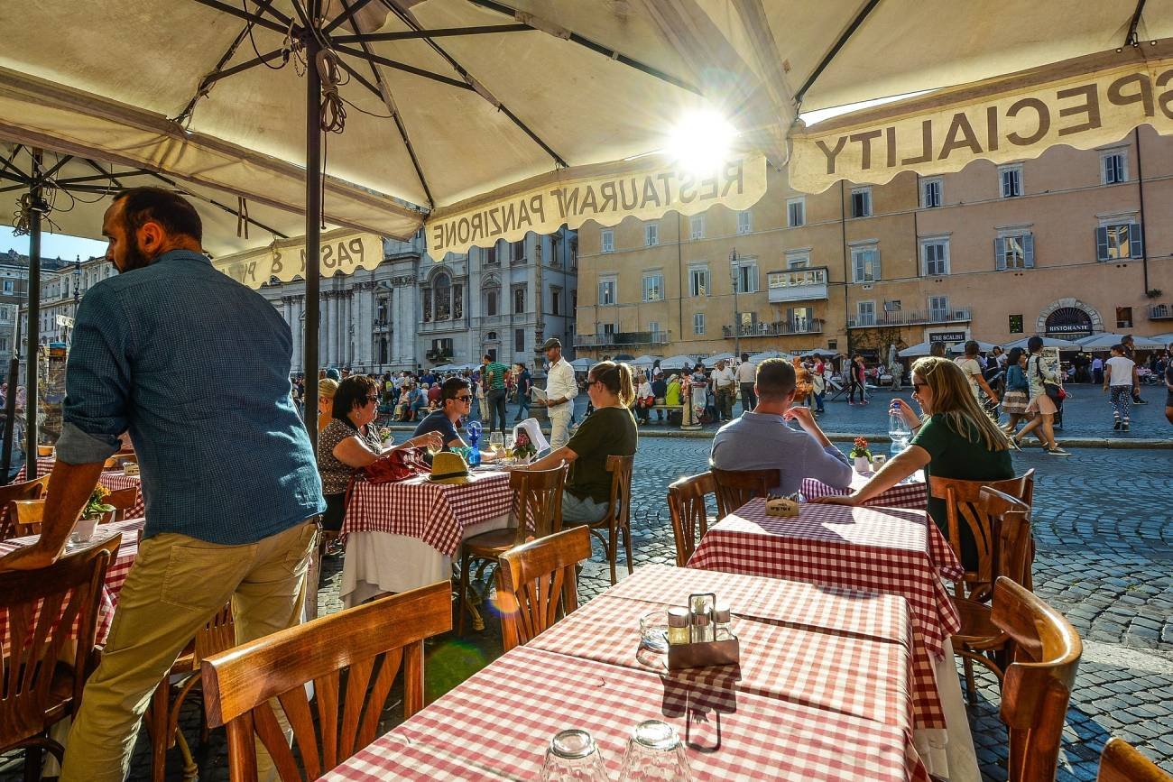 Letni ogródek restauracyjny. Kelner obsługujący gości.