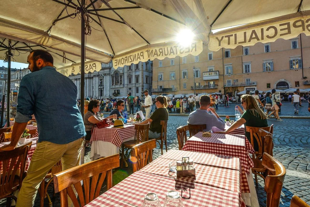Letni ogródek restauracyjny. Kelner obsługujący gości.
