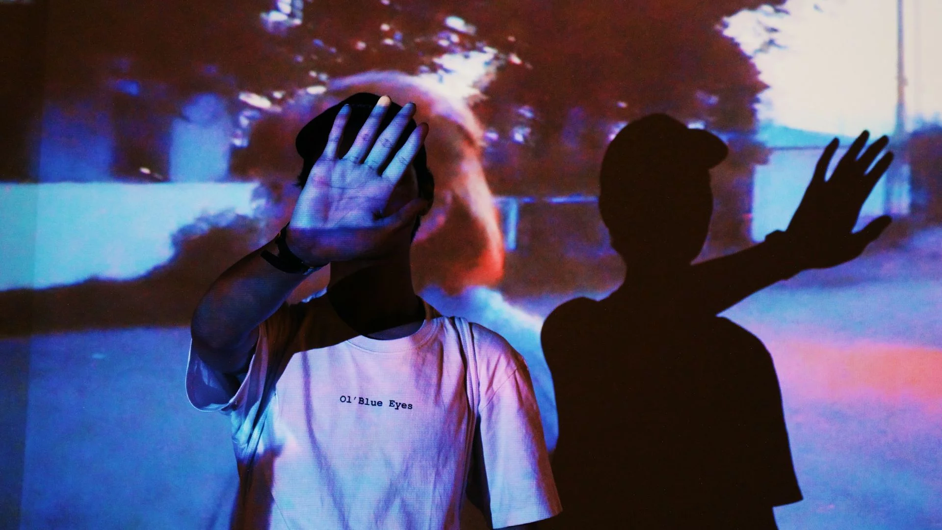 Polacy przenoszą kino do domu. Streaming w centrum zakupów Black Week Osoba zakrywająca ręką twarz przed światłem z rzutnika.