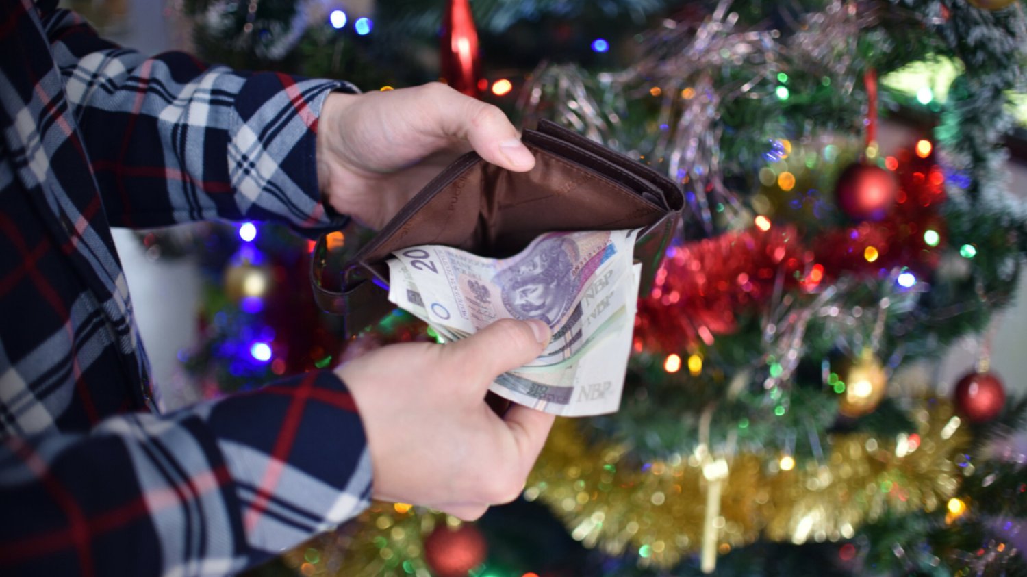Mężczyzna trzyma pieniądze na tle choinki