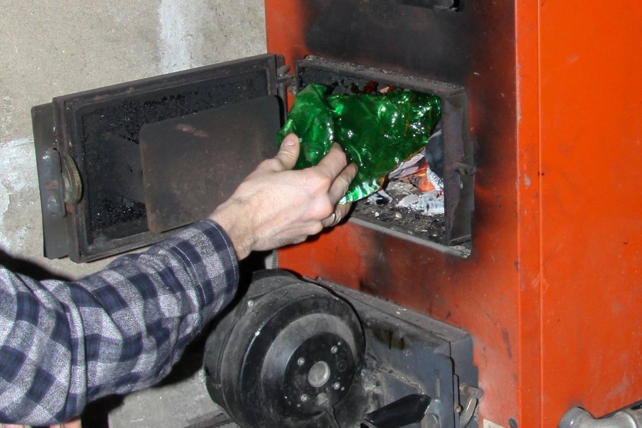 Mężczyzna wkłada do pieca plastikową butelkę