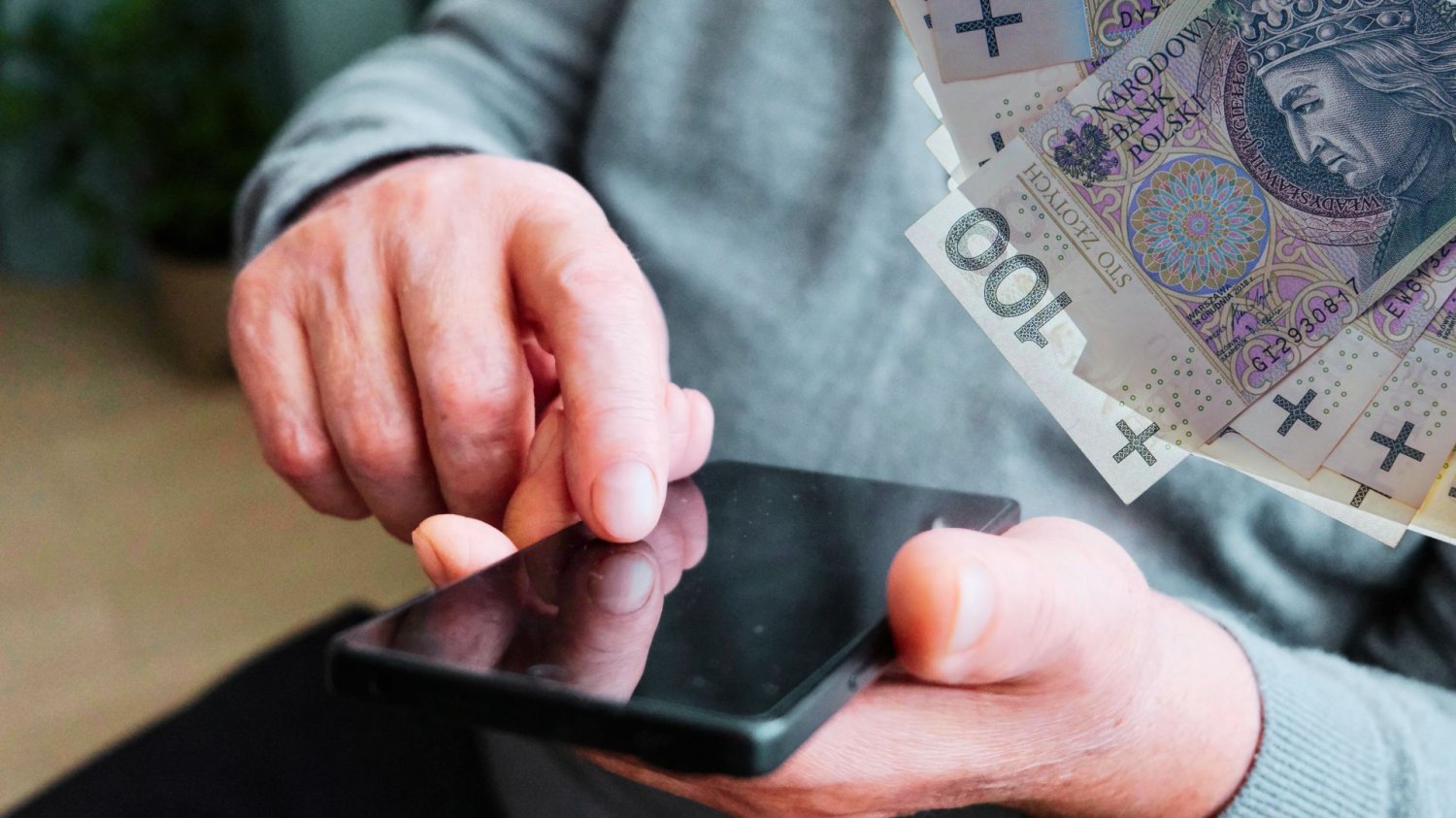 Kluby Rozwoju Cyfrowego dla polskich gmin. 976 mln złotych na walkę z cyfrowym wykluczeniem Człowiek korzystający z smartfona i banknoty 100 złotych. Kluby Rozwoju Cyfrowego dla polskich gmin. 976 mln złotych na edukację cyfrową dla dorosłych