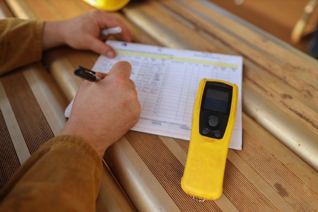 męskie dłonie na zapisujące na kartce informacje z alkomatu który leży obok mężczyzny