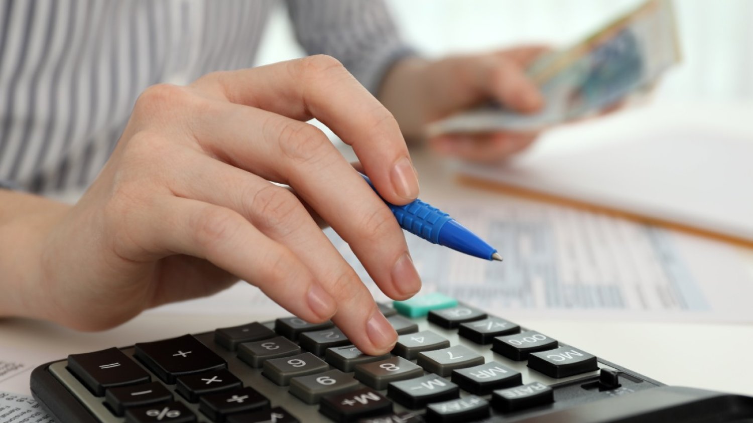 Zbliżenie na kobiecą ręką z długopisem używającą kalkulatora