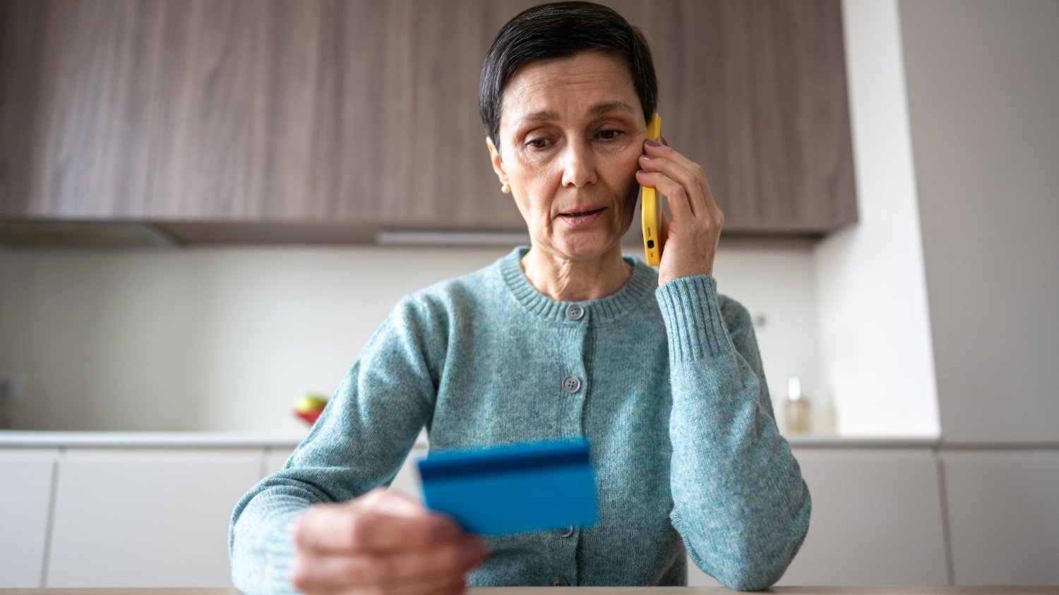 Oszuści wyłudzili 1,3 mln zł w Gorlicach. Zaufali "bankowi" i zostali z niczym Kobieta rozmawiająca przez telefon. W ręku trzyma kartę bankową.