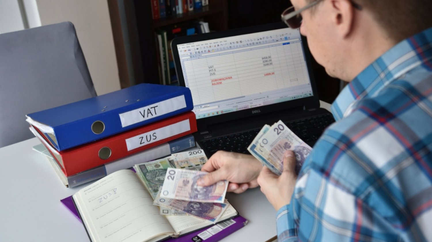 Mężczyzna, banknoty polskie, komputer.