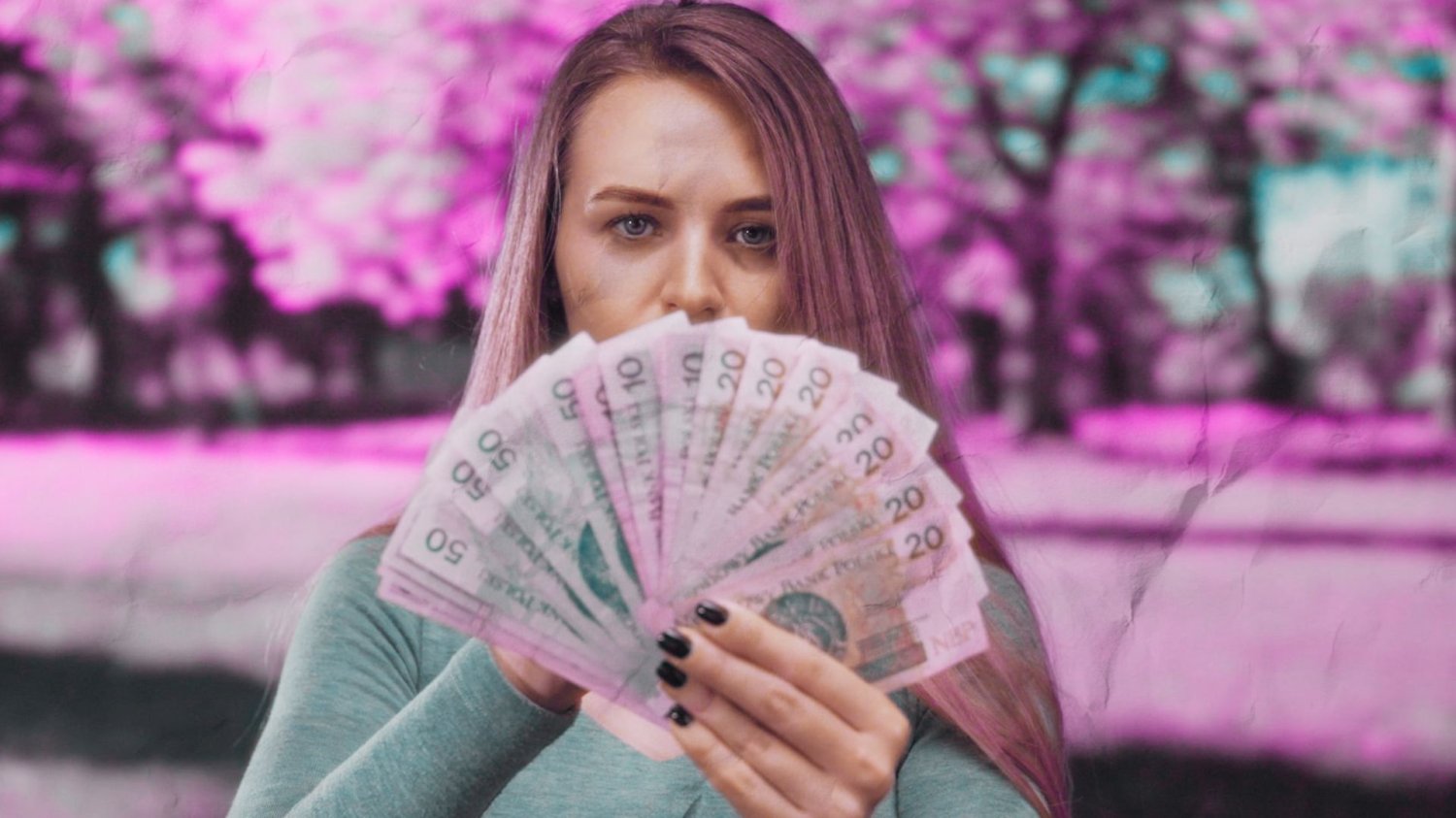 Kobieta trzymająca przed sobą polskie banknoty.