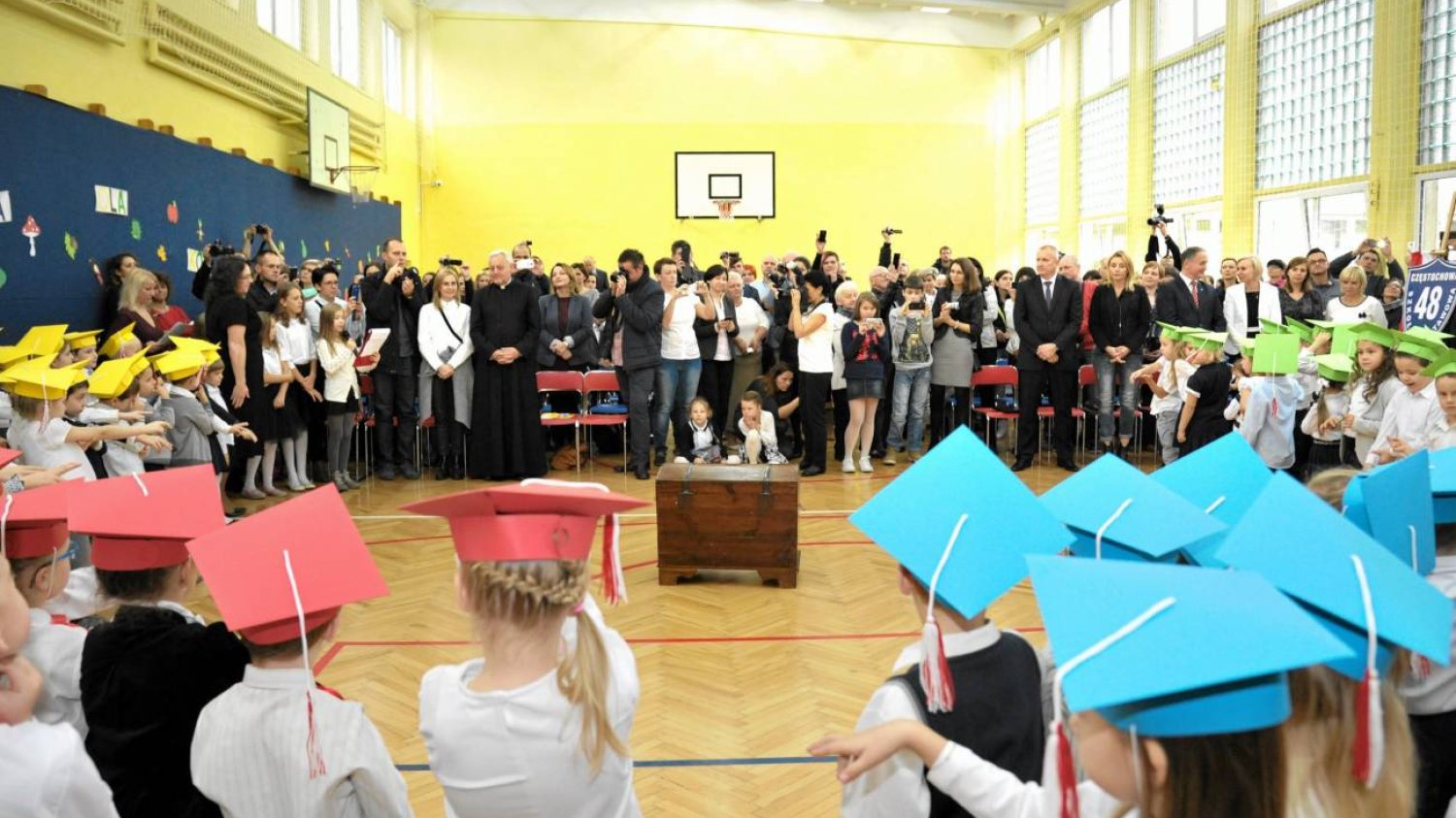 Uroczystość szkolna w szkole podstawowej. Zgromadzenie uczniów, nauczycieli i rodziców na sali gimnastycznej