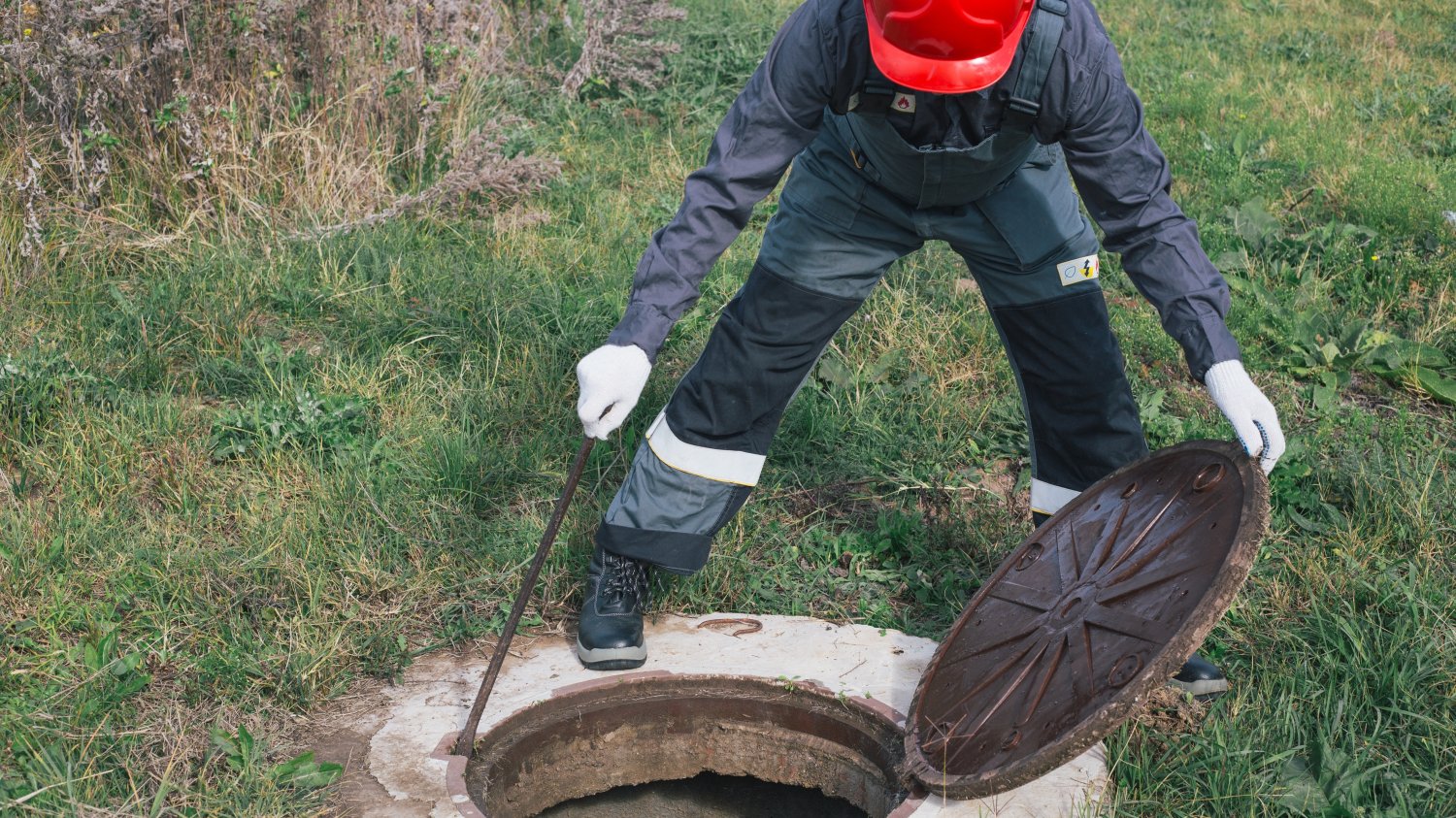 56 proc. gmin źle kontroluje ścieki. Szambo się wylało i znika poza systemem Osoba zaglądająca do studzienki. Kontrola ścieków w gminach to fikcja. Szambo się wylało i znika poza systemem