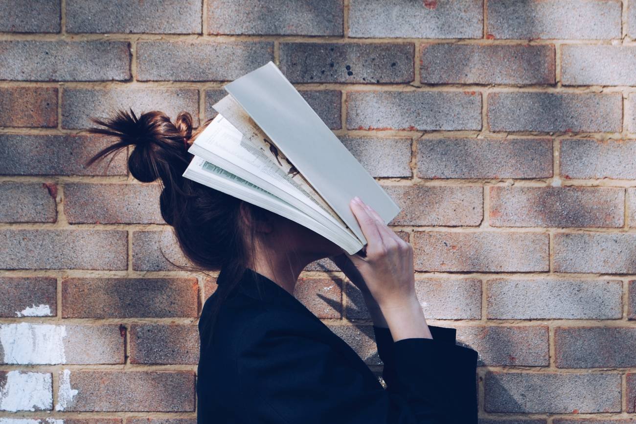 kobieta zakrywa twarz książką