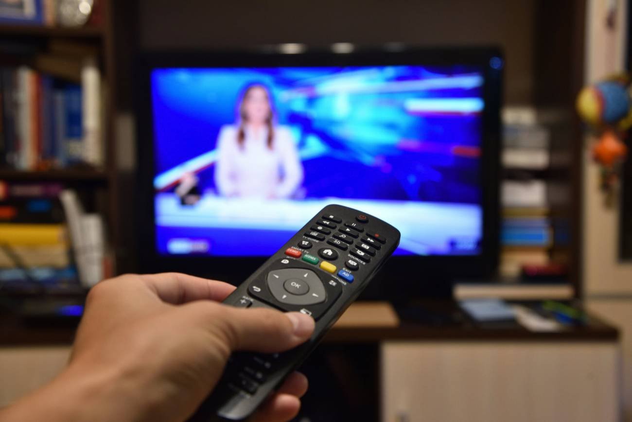 Osoba z pilotem ogląda TVP Info.