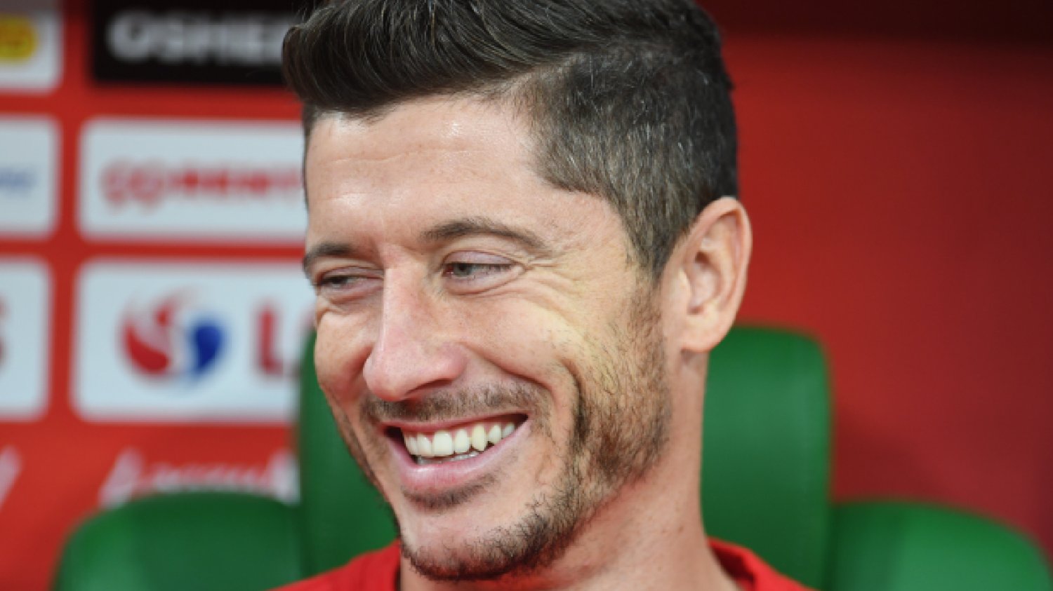 uśmiechnięty Robert Lewandowski patrzy w bok na konferencji prasowej w sprawie piłki nożnej