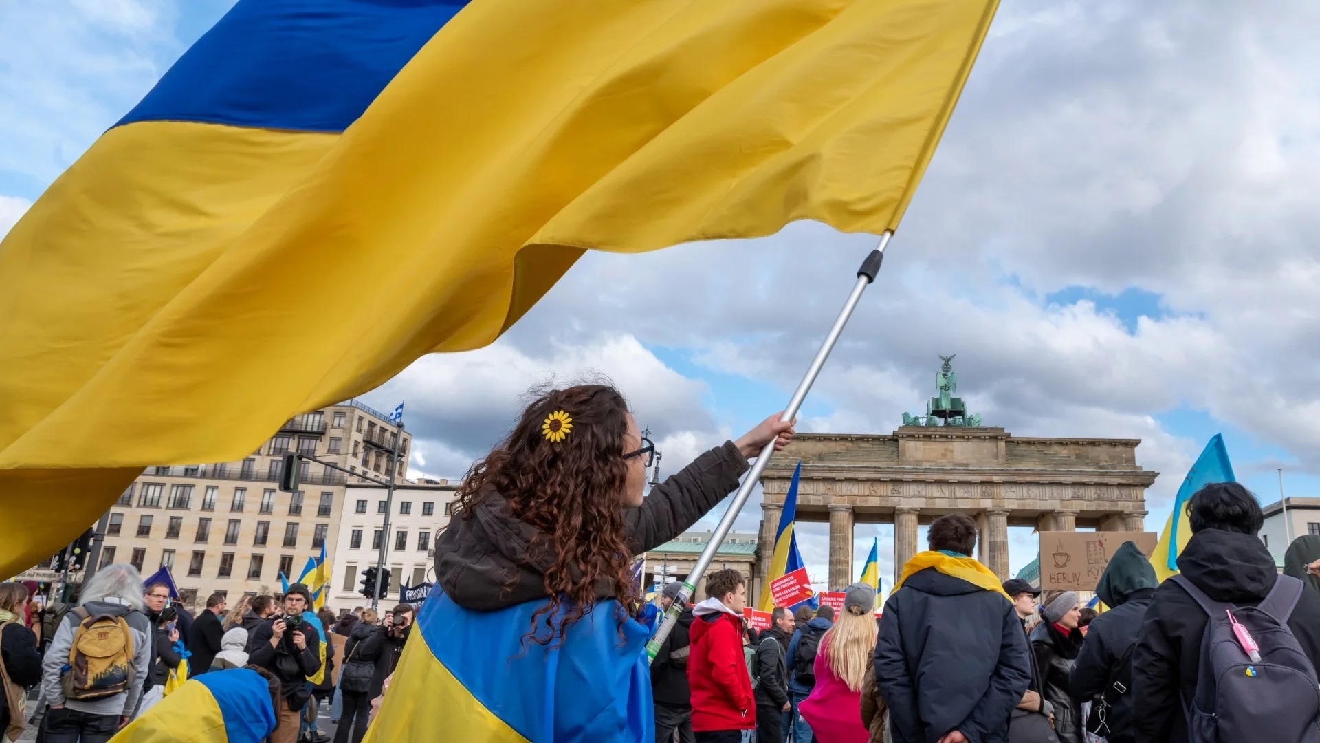 Grupa ludzi powiewająca ukraińskimi flagami w Berlinie.