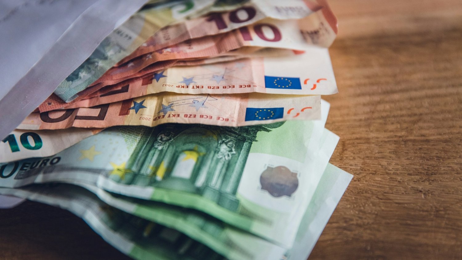 Niemcy zmieniają zasady dotyczące zasiłków. Banknoty euro w otwartej kopercie na stole. Niemcy zmieniają zasady dotyczące zasiłków.